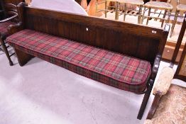 A traditional oak pew, with bespoke cushion in red tweed , width 190cm