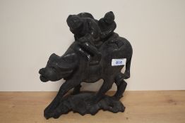 A Chinese carved hardwood figure group, a man and child riding a water buffalo, appears fire damaged