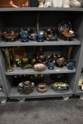 Three shelves of Carnival glassware in different colours from blue, green, red and amber, the