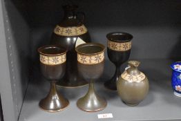 A studio pottery stoneware decanter, jug and three goblets, each with a stencilled and unglazed band