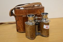 A pair of leather cased and embossed leather mounted field glasses, of traditional form with