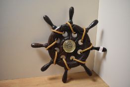 A mid-20th Century stained oak ship's wheel barometer, having a champagne coloured dial and