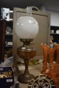 A vintage brass oil lamp with shade and chimney.