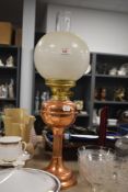 A vintage copper and brass oil lamp with a column style base, having chimney and shade.