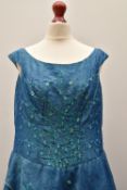 A 1950s formal evening or bridesmaid dress in aqua silk taffeta, featuring a wide neckline and off-