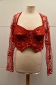A 1990's 'Tropical Climax' red button-up bustier, has long sleeves with scalloped hems and a Queen-