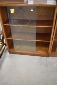 A vintage low bookcase, in the Herbert Gibbs style with etched glass sliding doors