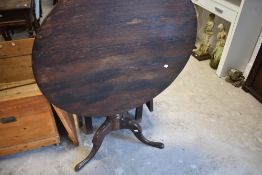 A George III oak snap-top pedestal table, the planked top over snap-top action and turned gun-barrel