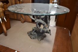 A modern coffee table having circular glass top on cast 'bronzed' base, modelled as lion on tree