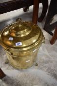 A cylindrical brass coal bin with domed finial topped cover, metal liner, carrying handles and short