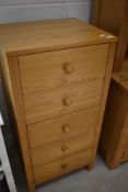 A modern golden oak narrow chest of five drawers