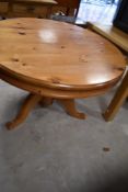 A modern circular pine pedestal table, having large central turned support issuing three down