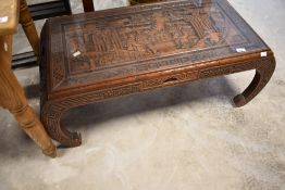 An Oriental coffee table having carved decoration and glass top, approx. 101 x 46cm