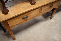 A Victorian pine two-drawer side table, having a rectangular planked top over two drawers and turned