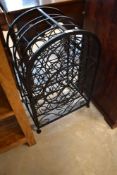 A modern metal wine rack, of arched form with hinged door decorated with open scroll work, divisions