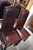 A set of four reproduction upholstered oak dining chairs, each having arched and padded backs,