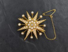 A yellow metal seed pearl and diamond star brooch, the central diamond in a decorative pearl