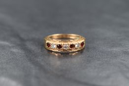 A 9ct gold seven stone garnet and cubic zirconia band ring having cut detail to mount, ring size P