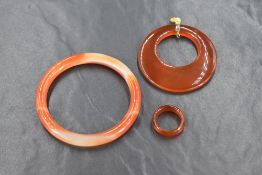 A small orange agate bangle, internal diamater approx 55mm, a matching band ring, size J and a