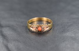 A 15ct gold coral and diamond ring, the central cabochon flanked by diamond chips and two further