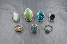 Seven white metal rings, all stamped silver/925, all having green stone/shell or enamel