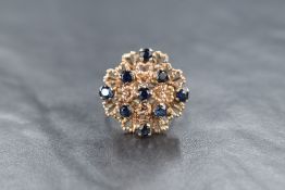 A modern 18ct gold sapphire ring, the nine round cut sapphires set in a contemporary multi-level