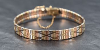 A 9ct tricolour gold articulated band bracelet having engraved decoraion and concealed clasp, approx