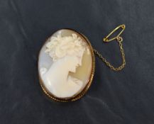A 9ct gold shell cameo brooch depicting a lady in profile, adorned with flowers, within a bezel