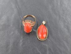 An oval coral cabochon ring having a four claw setting on a filligree wire mount on a yellow metal