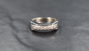 A white metal diamond band, the seven round cut diamonds measuring approximately 0.21 total,