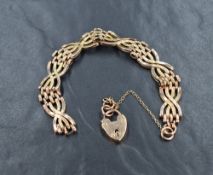 A rose metal four bar twist gate bracelet marked 9ct, having a heart padlock and safety chain, 14.