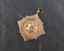A 9ct rose gold medallion pendant, having a central star motif to the front and engraving to the