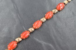 A yellow metal articulated bracelet stamped 18K having four coral set panels interspersed by