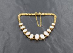 An 18ct gold opal bracelet, the eleven graduated oval cabochon opals in claw settings on an 18ct
