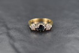 An 18ct gold sapphire and diamond trilogy ring, the central round cut sapphire measuring