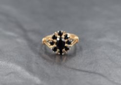 A 9ct gold sapphire cluster ring, the central oval cut sapphire measuring approximately 0.70ct, with