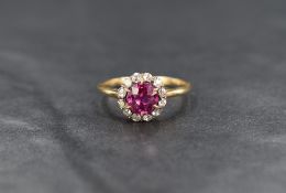 A yellow metal pink sapphire and diamond cluster ring, the round cut pink sapphire measuring