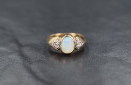 A 9ct gold opal dress ring having a trio of diamond chips to each shoulder on a 9ct gold moulded