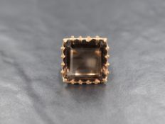 An oversized smoky quartz ring having a square stone in a claw set raised basket mount with engraved