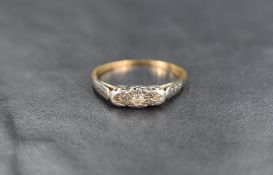 An 18ct gold three stone diamond ring, the three illusion set diamonds in a platinum setting on an