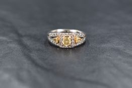An 18ct white gold diamond ring, the central cushion cut yellow diamond measuring approximately 0.