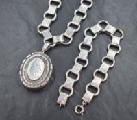 A large silver locket on a statement silver chain, with decorative floral engraving along with a
