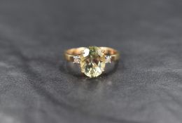 A 9ct gold peridot and diamond ring, the oval peridot being flanked by two small diamonds, all in