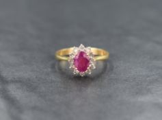 An 18ct gold ruby and diamond cluster ring having a small oval ruby surrounded by twelve small