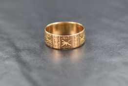 An 18ct gold band, having engraved decorative sunburst panel motifs, ring size P-Q, 3.9g