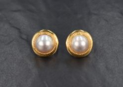 A pair of 18ct gold button pearl earrings, the large pearls within a bezel setting with twist