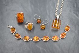 An assortment of silver amber jewellery, comprising a chunky rectangular ring, an oval ring with