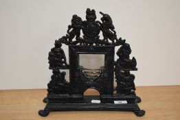 A Victorian cast iron painted door porter in the form of a heraldic miniature fireplace with coat of