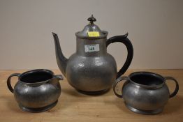 A three piece Tudric pewter part tea service, of planished appearance, and comprising a teapot,