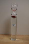 A modern clear glass and red sand egg timer, encased in a water filled clear glass cylinder, when